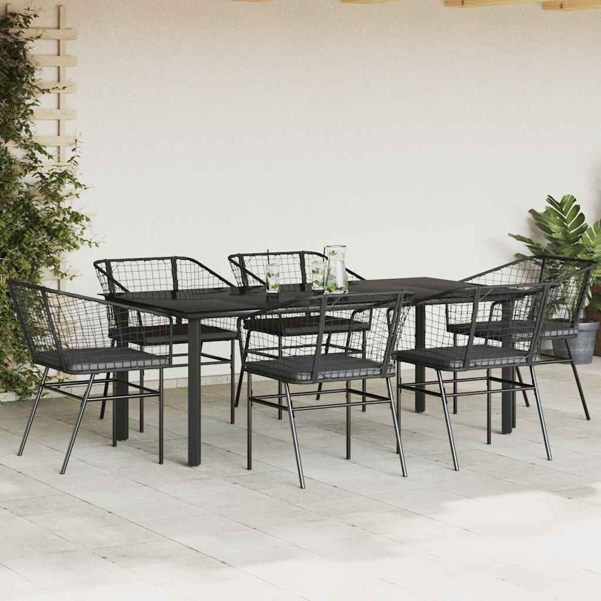 Juego de comedor exterior de metal negro con respaldos y asientos de malla, mesa oscura y fondo claro.