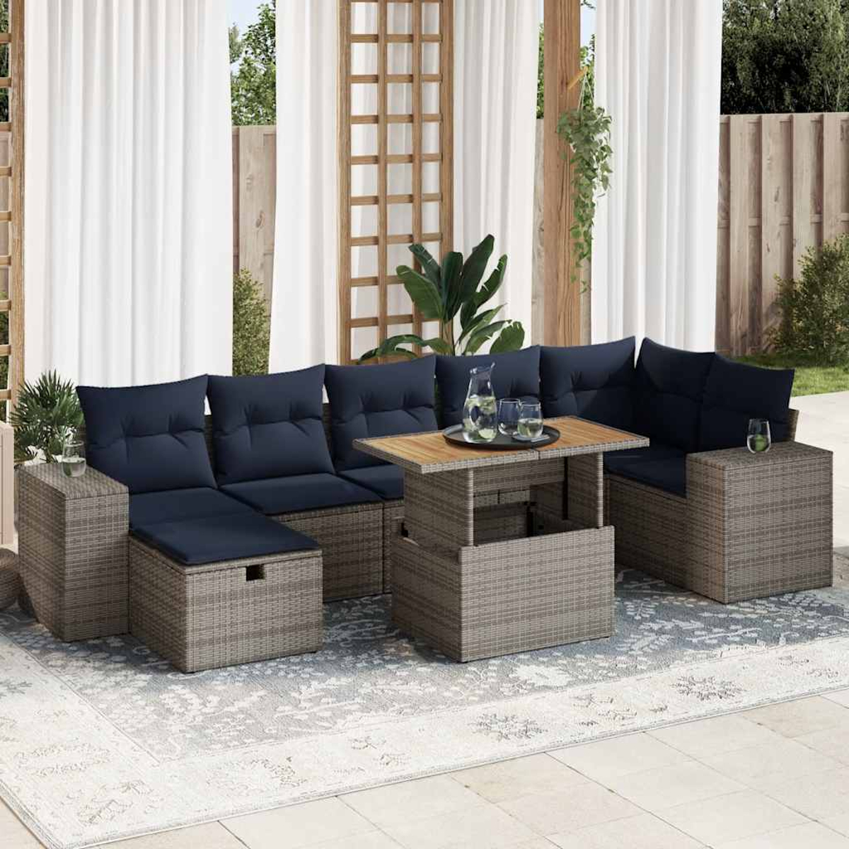 Outdoor-Ecksofa mit blauen Kissen, einem Tisch mit Holzplatte und Beistelltischen. Auf einem hellfarbigen Teppich.