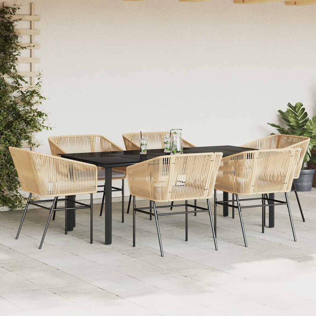 Gartenmöbel mit sechs geflochtenen Stühlen um einen schwarzen Tisch auf einer Terrasse, Pflanzen im Hintergrund.