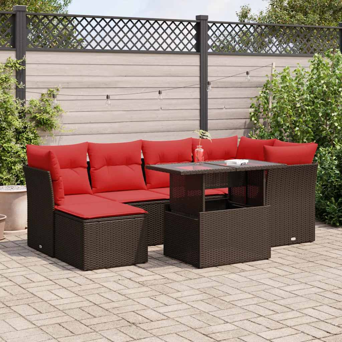 Gartenmöbelset mit roten Kissen und dunklem braunen Korb. Auf einer Terrasse mit Zaun im Hintergrund.