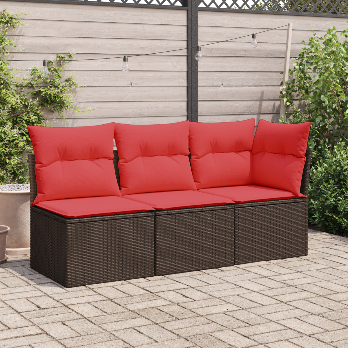 Ein braunes Outdoor-Sofa aus Korbgeflecht mit drei roten Kissen und Sitzfläche.