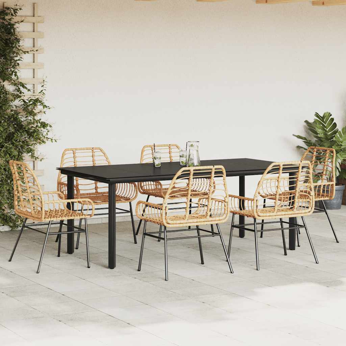 Juego de comedor exterior con sillas naturales y una mesa negra. Se ven plantas y bebidas.