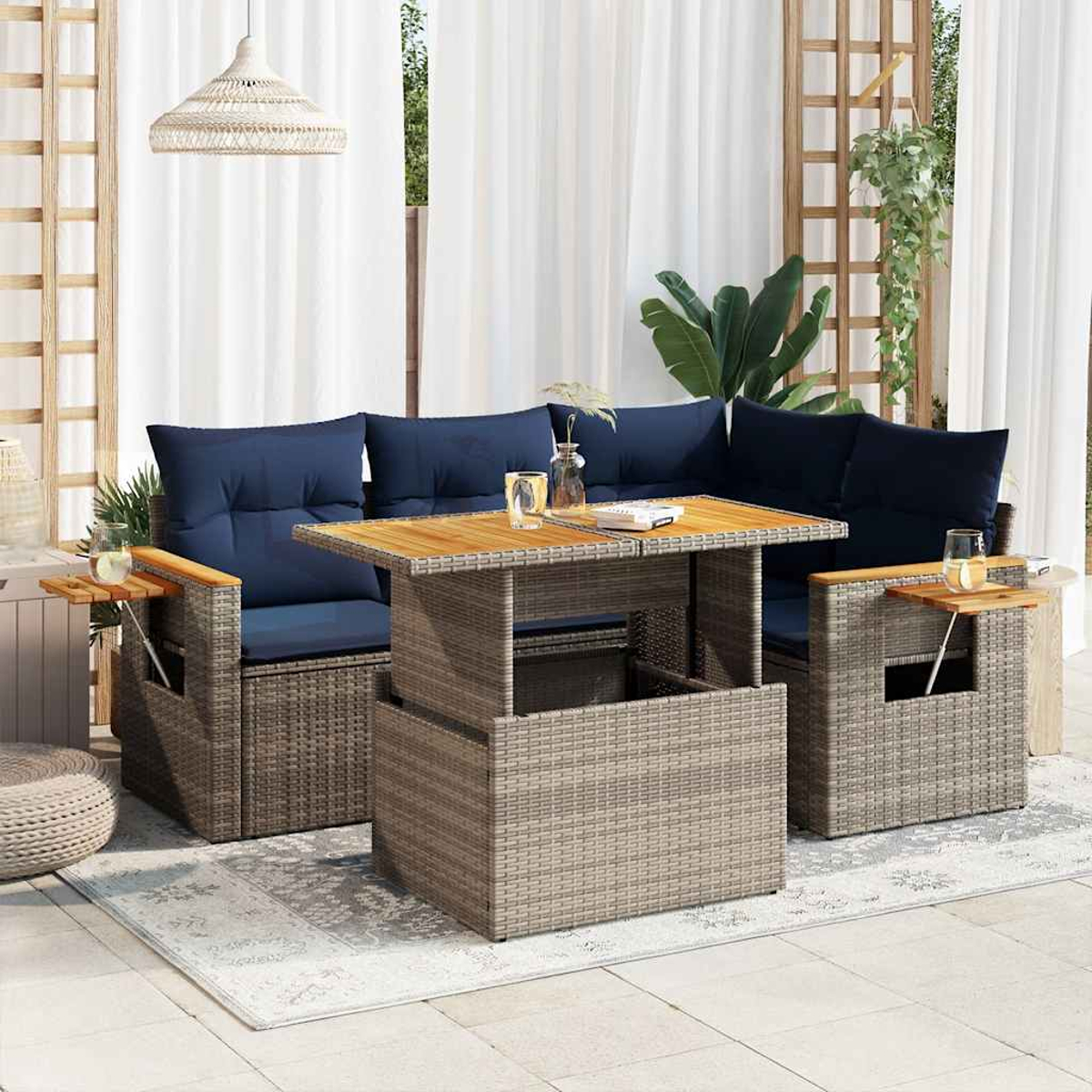 Terrassenset für den Außenbereich mit Tisch, Sofas und Beistelltischen. Blaue Kissen, Rattanrahmen.