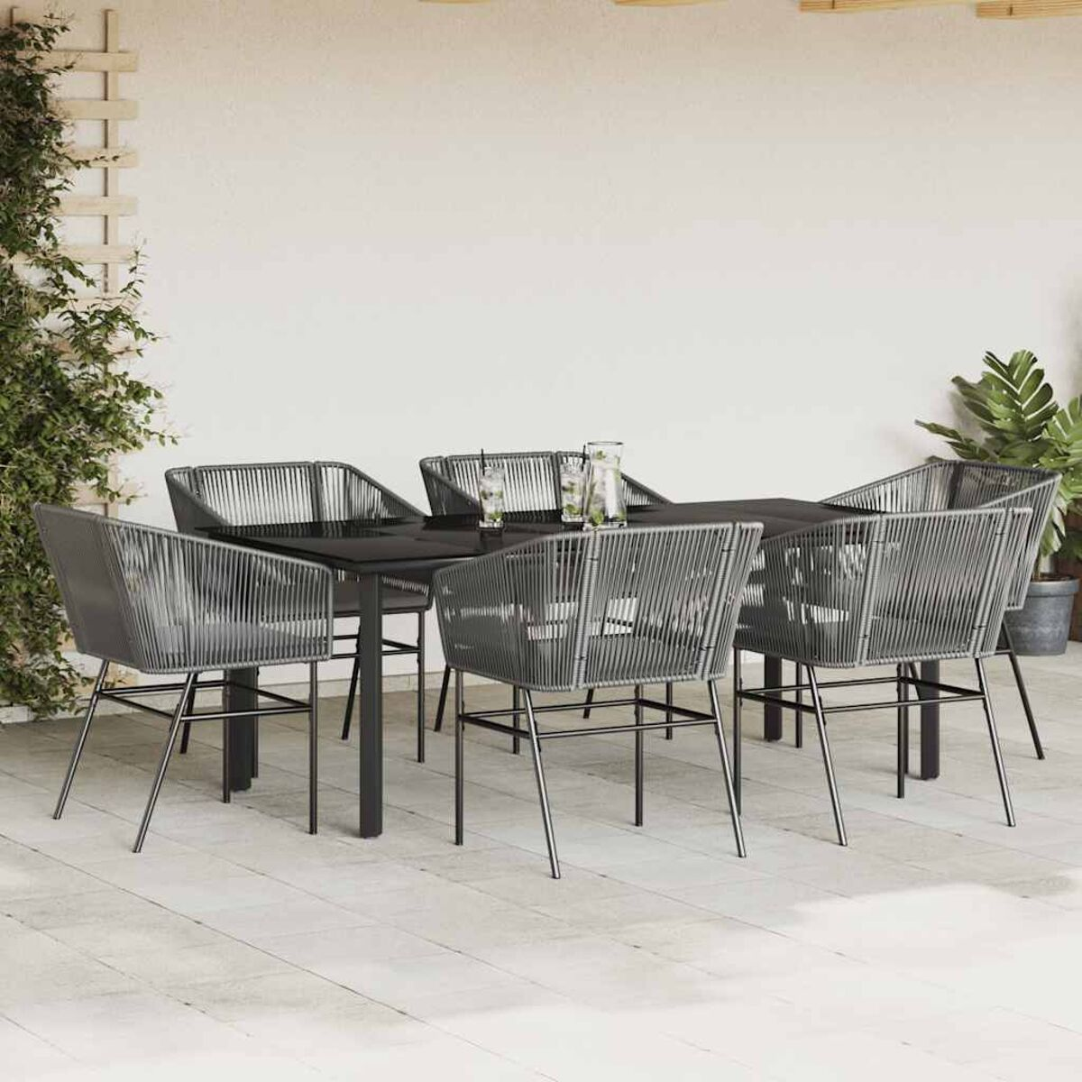 Essgruppe für den Außenbereich mit einem schwarzen Glastisch und sechs grauen Seilstühlen auf einer Terrasse.