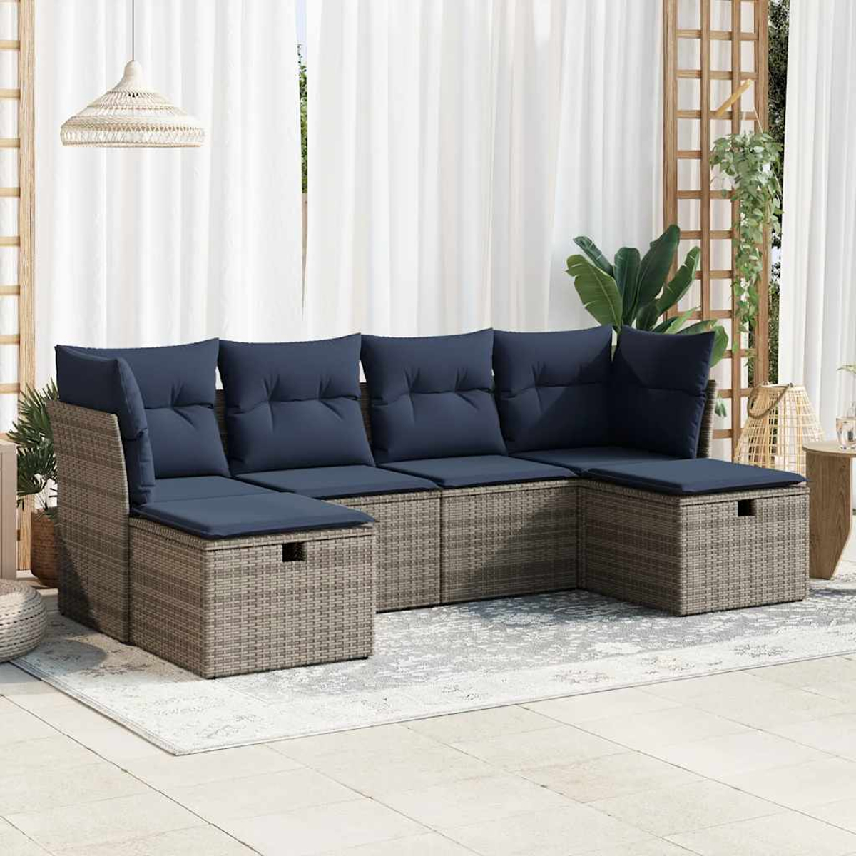 Korbssofa-Set mit blauen Kissen. Outdoor-Setting auf einem gemusterten Teppich mit Vorhängen.