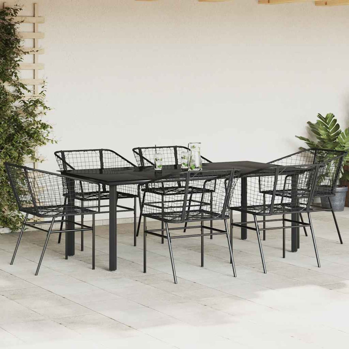 Juego de comedor al aire libre con sillas y mesa negras, bebidas en la mesa y plantas.
