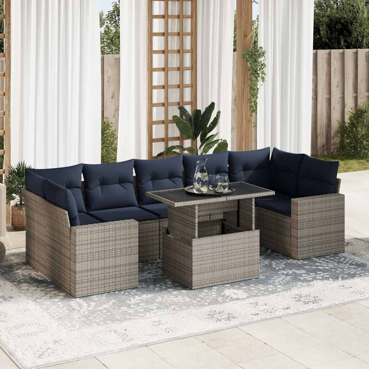 Outdoor-Sitzgruppe mit grauem Korbgeflecht, blauen Kissen und Tisch. Vorhänge im Hintergrund.