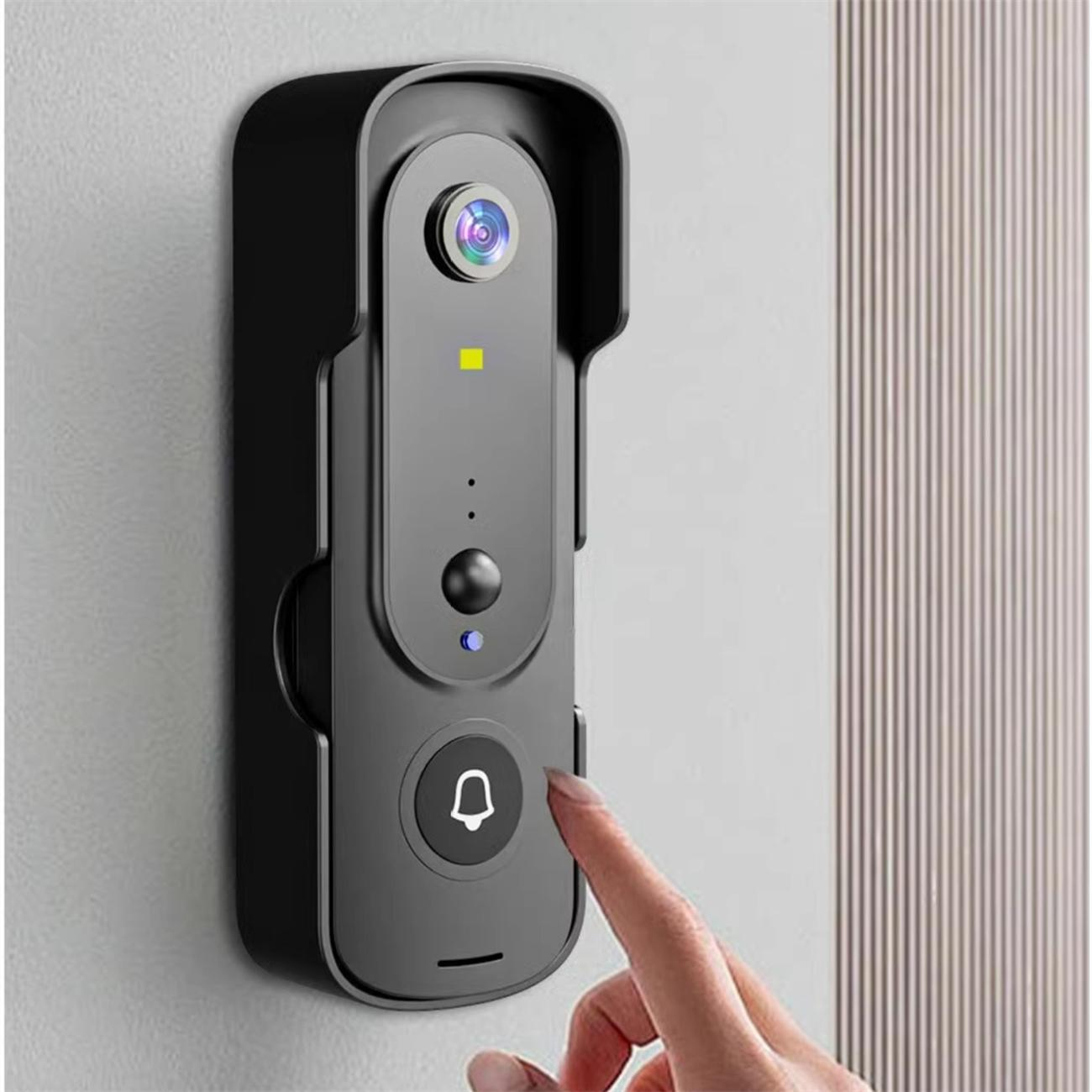 Schwarze Türklingelkamera an der Wand. Eine Hand drückt die Klingeltaste.