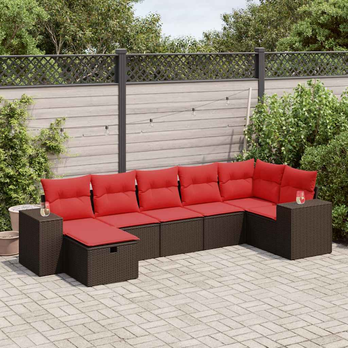 Dunkelbraunes Ecksofa aus Korbgeflecht mit roten Kissen und einer Aufbewahrungshocker.