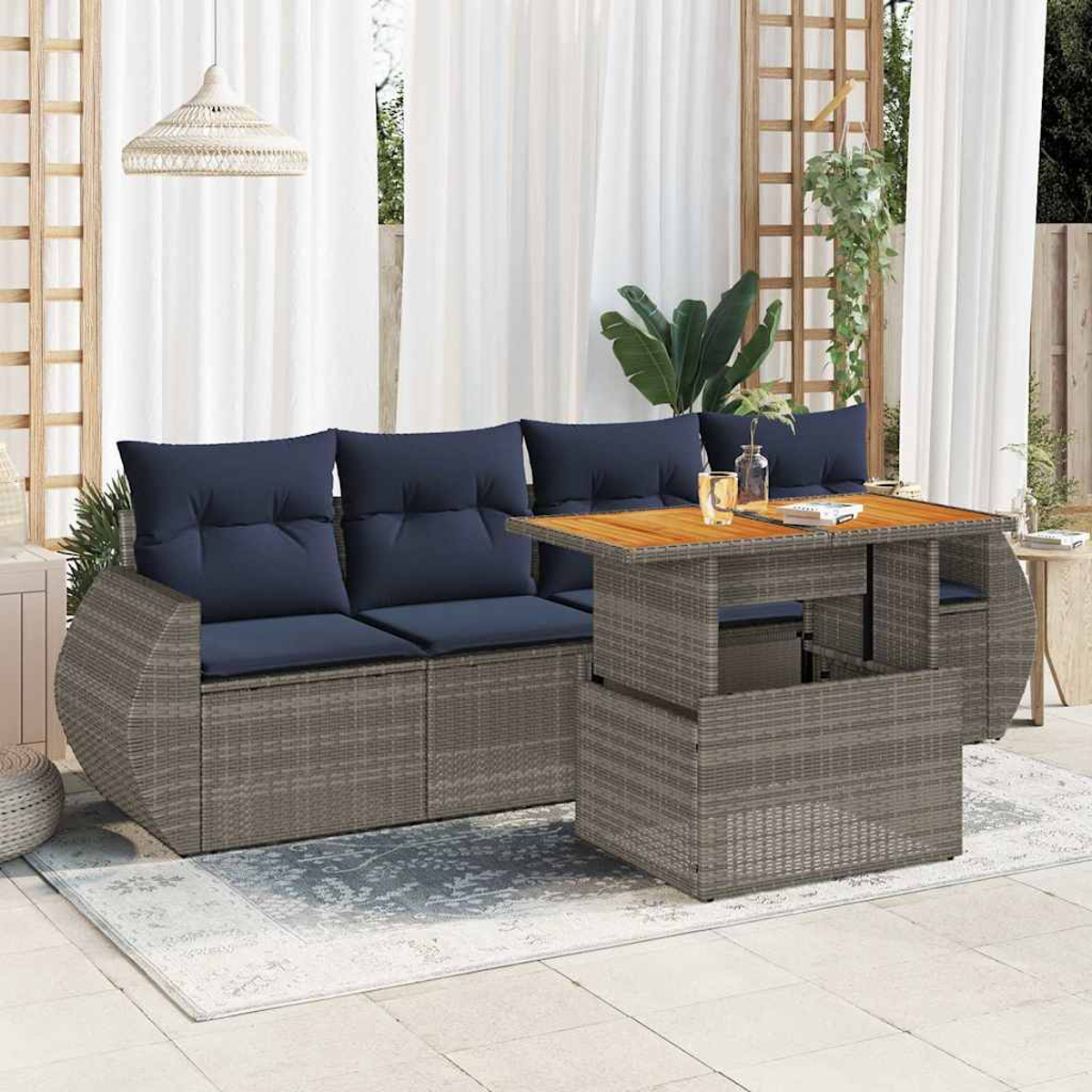 Juego de sofás de ratán en forma de L con mesa elevable, cojines azules y tapa de madera al aire libre.