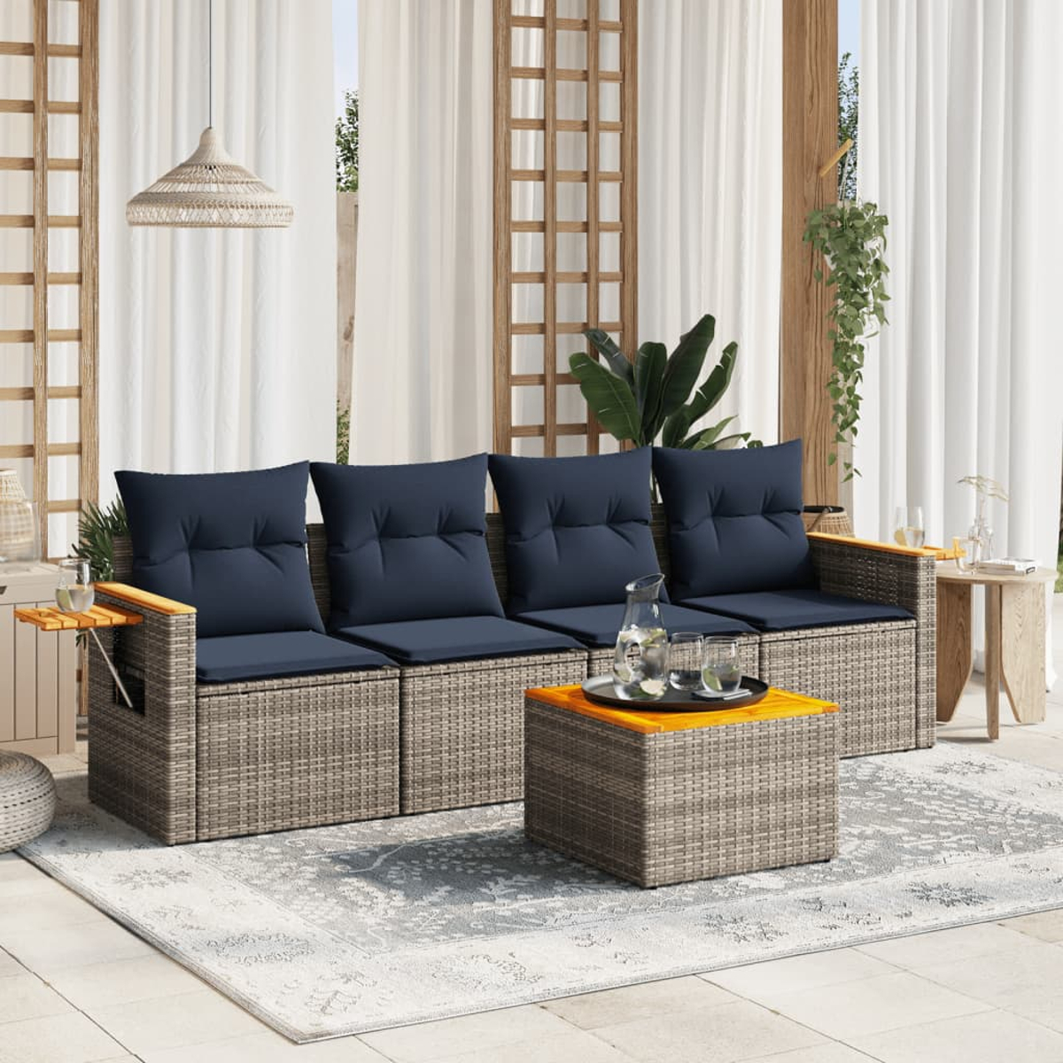 Ein Terrassenset mit Sofa, Armlehnen und Couchtisch. Blaue Kissen und ein Teppich.