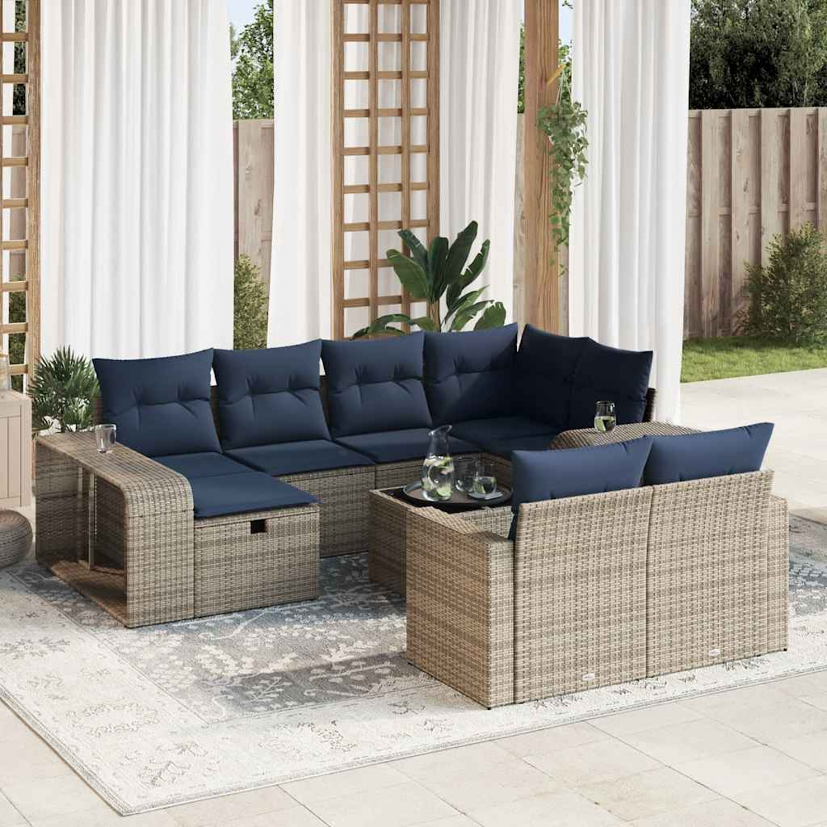 Ein Ecksofa aus Korbgeflecht mit blauen Kissen steht auf einer Terrasse, im Hintergrund durchsichtige Vorhänge.