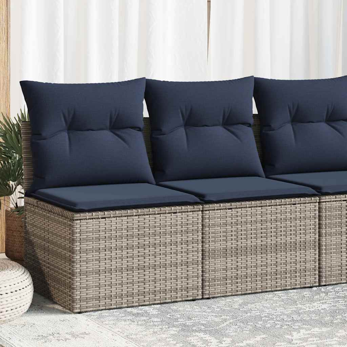 Nahaufnahme eines gewebten Outdoor-Sofas mit blauen Kissen. Weiße Vorhänge sind im Hintergrund.