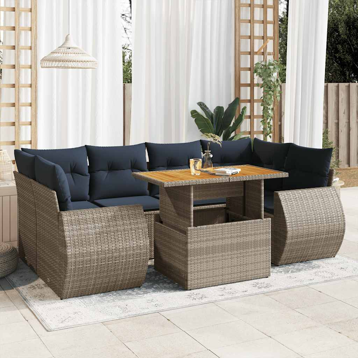Juego de patio con cojines azules, mesa de madera y cortinas blancas.