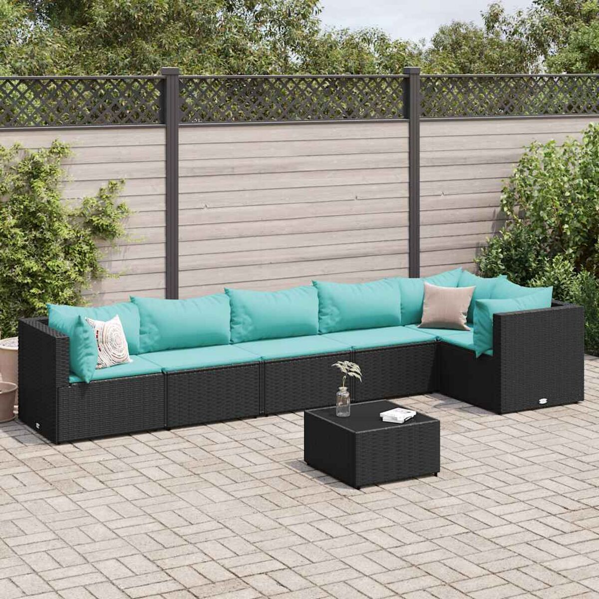 L-förmiges schwarzes Outdoor-Sofa aus Korbgeflecht mit türkisfarbenen Kissen und einem schwarzen Couchtisch auf einer Backstein-Terrasse.