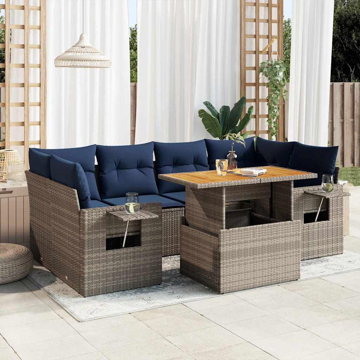 Graues Rattan-Outdoormöbel-Set mit blauen Kissen, einem Holztisch und Pflanzen.