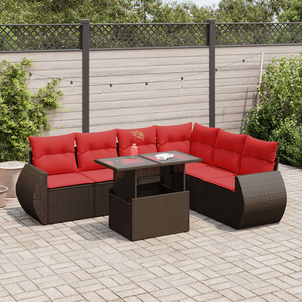 Outdoor-Ecksofa aus Korbgeflecht mit roten Kissen und einem Tisch mit Glasplatte. Auf Backstein-Terrasse.
