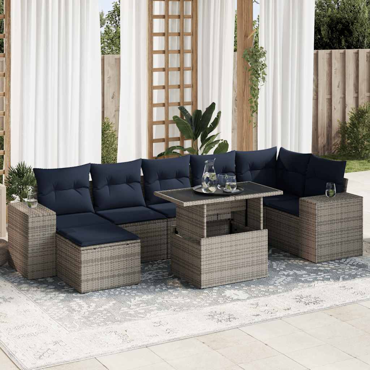 Seccional exterior con cojines azules, mesa elevable. El seccional es de mimbre, con alfombra estampada.