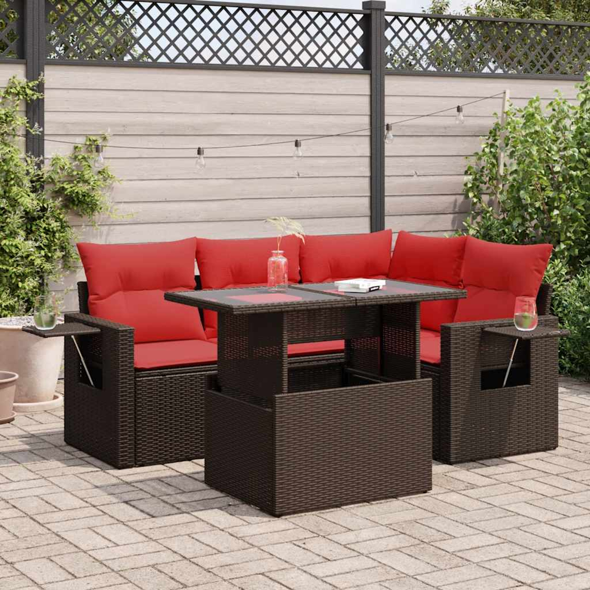 Geflecht-Terrassenmöbel mit roten Kissen. Tisch mit Getränken. Ziegel-Patio mit Pflanzen.