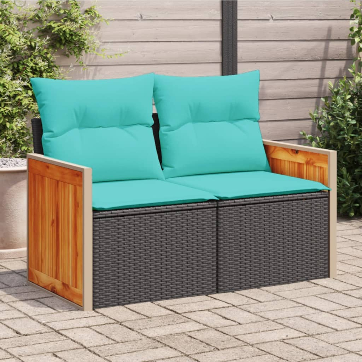 Ein Zwei-Sitzer-Outdoor-Sofa mit türkisfarbenen Kissen und einem dunklen Rattansockel.