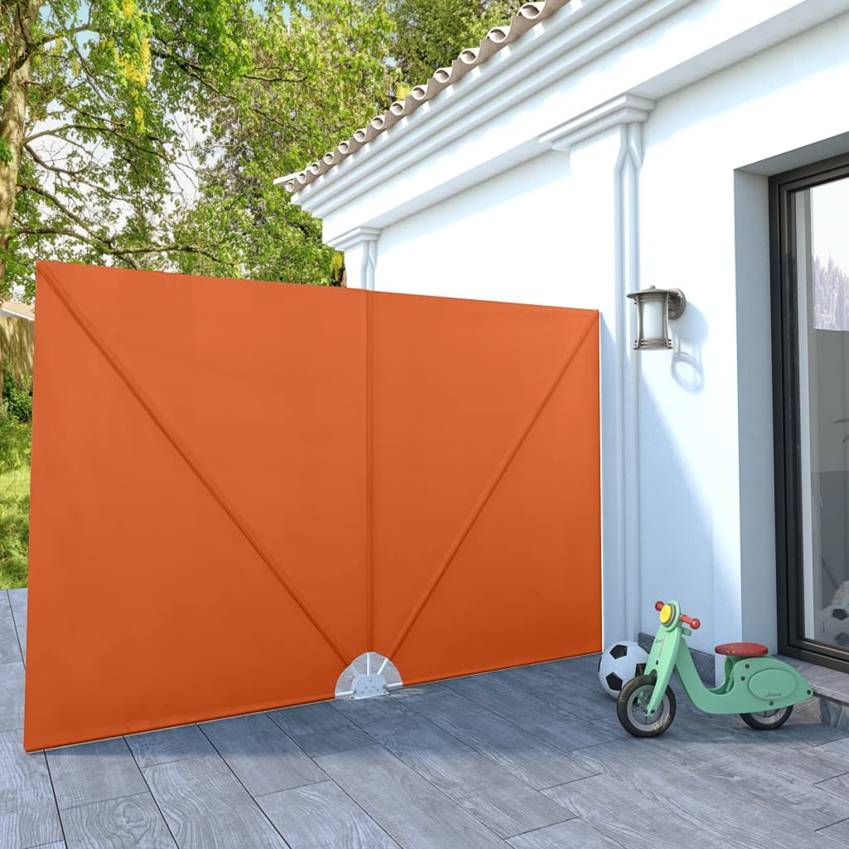 Eine orangefarbene geometrische Wand. Ein grüner Roller und ein Fußball befinden sich im Vordergrund.