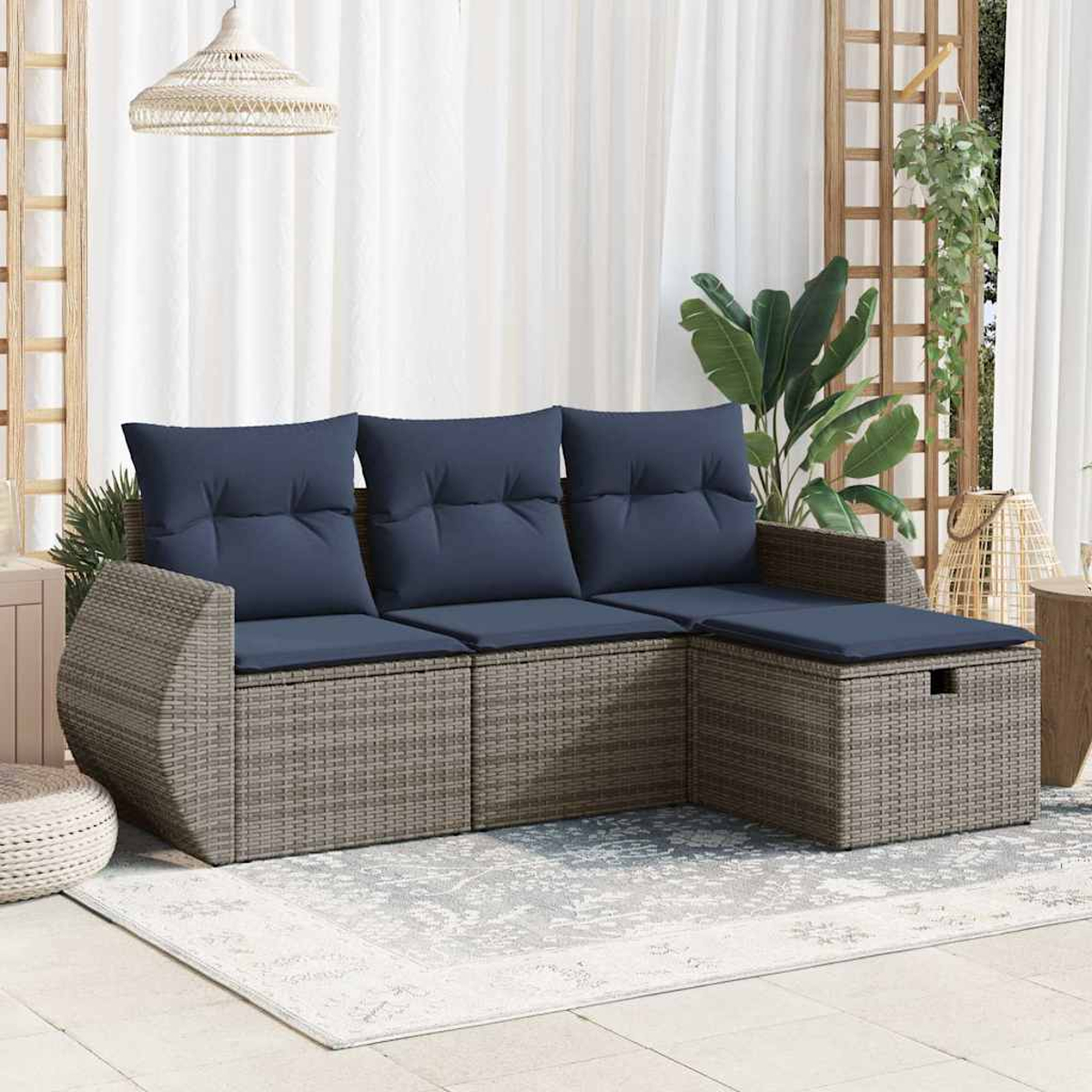 Ein graues Outdoor-Ecksofa mit dunkelblauen Kissen, auf einem Teppich, mit Pflanzen.