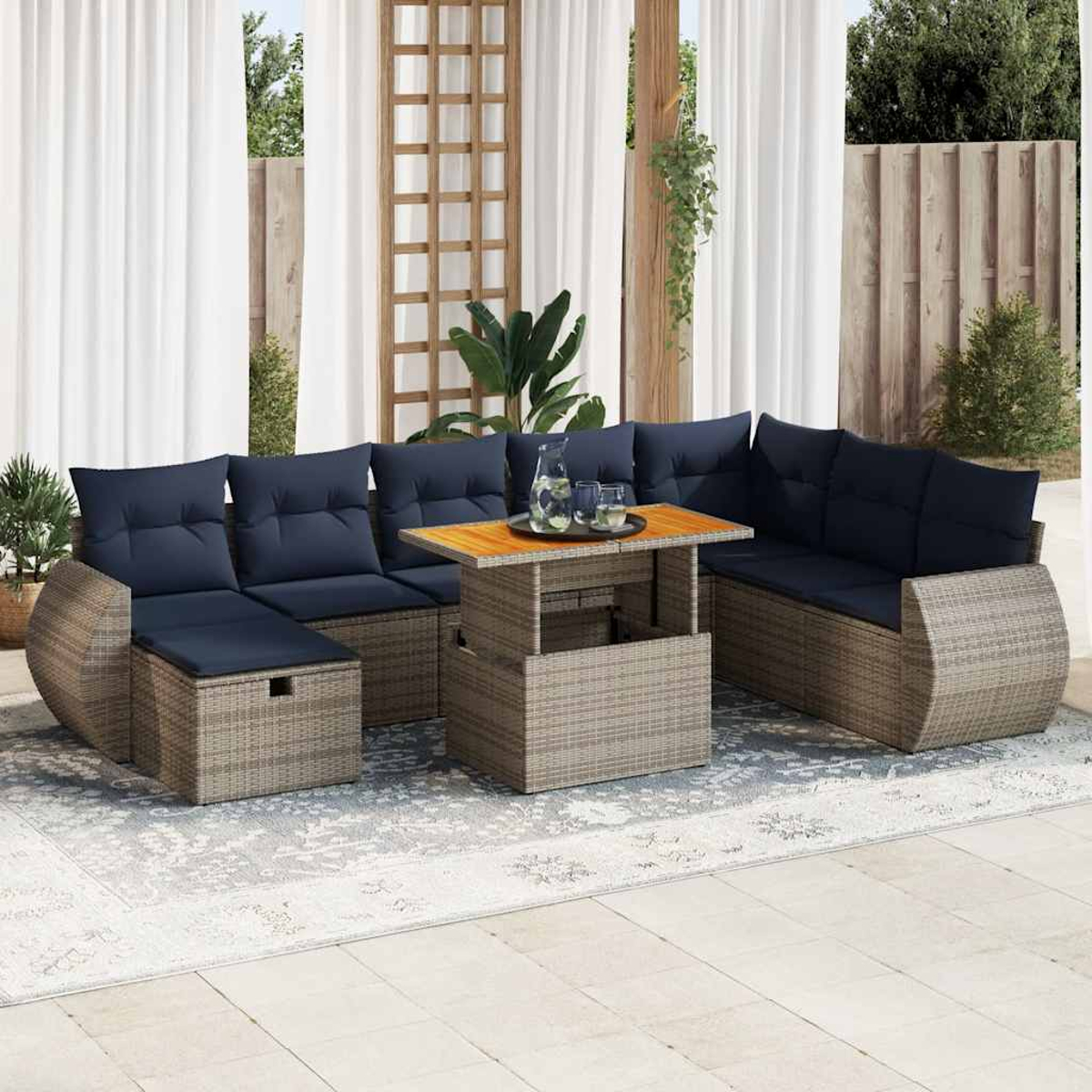 Outdoor-Rattansofa-Set mit blauen Kissen und einem Holztisch mit Gläsern, auf einem hellfarbigen Teppich.