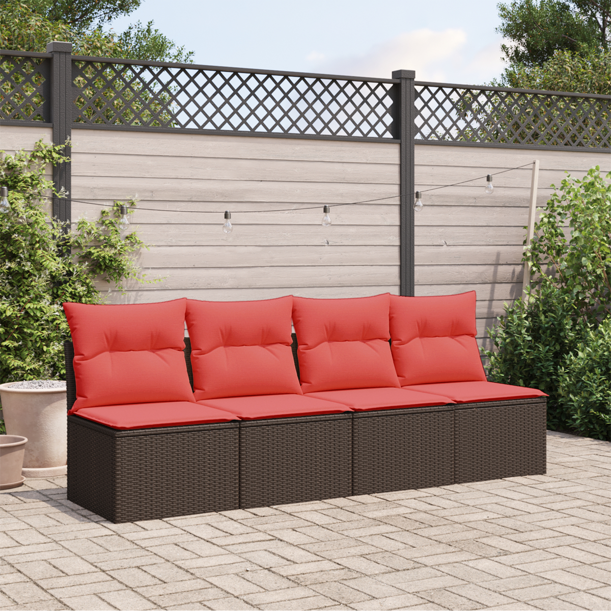 Ein braunes Outdoor-Sofa mit roten Kissen steht auf einer Backstein-Terrasse. Ein Gitterzaun im Hintergrund.