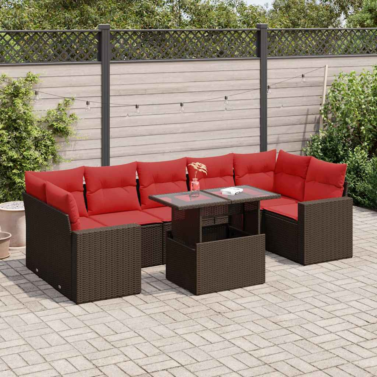 Outdoor-Korb-Möbelset mit roten Kissen und einem Tisch. Der Tisch befindet sich zwischen zwei Sitzbereichen. Braune Farbe.