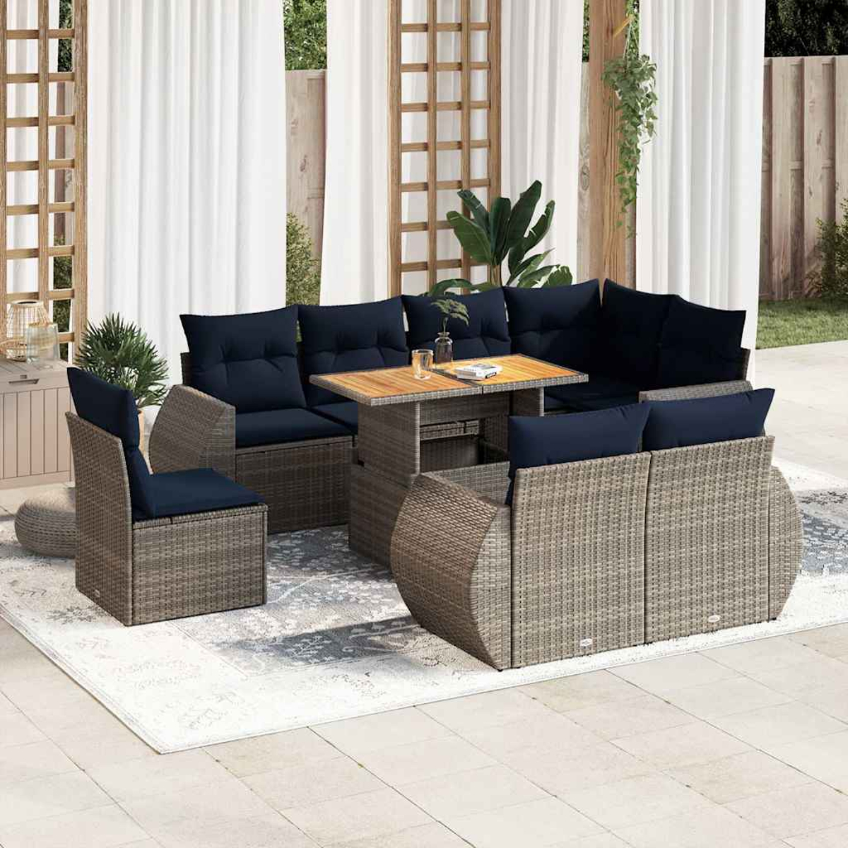 Graues Korbstoffsofa mit blauen Kissen und Tisch auf Terrasse. Weiße Vorhänge im Hintergrund.