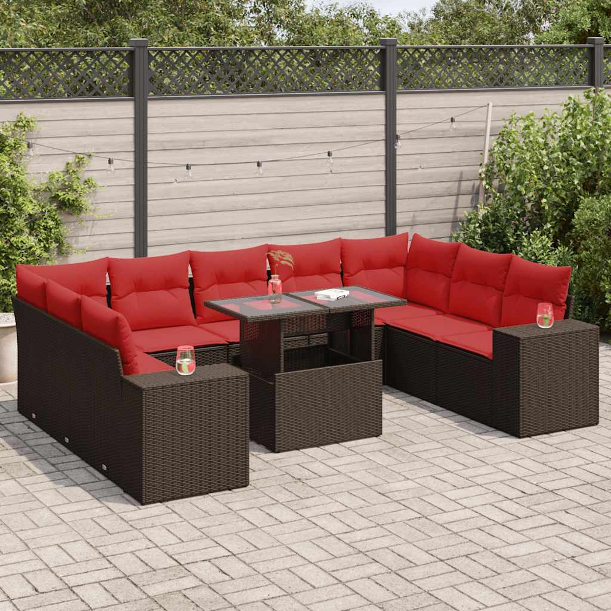 Rattan-Ecksofa für den Außenbereich mit roten Kissen und einem Glastisch auf einer Terrasse.