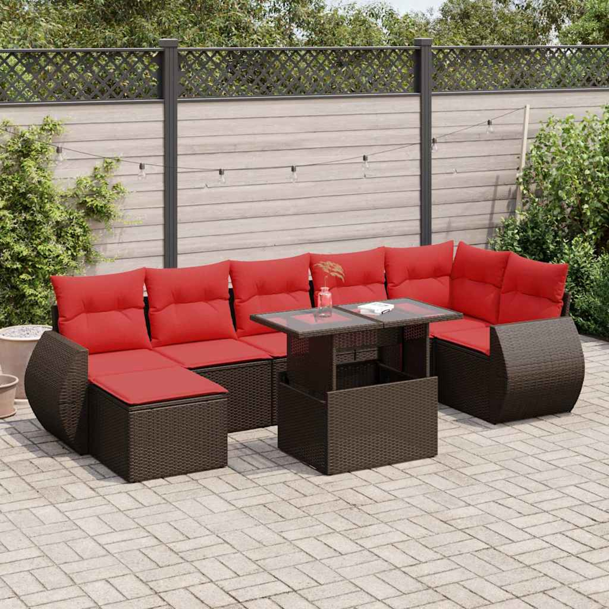 Ein Terrassenset mit roten Kissen auf einem braunen Korbgeweberahmen. Es hat einen Tisch und ein Ecksofa.