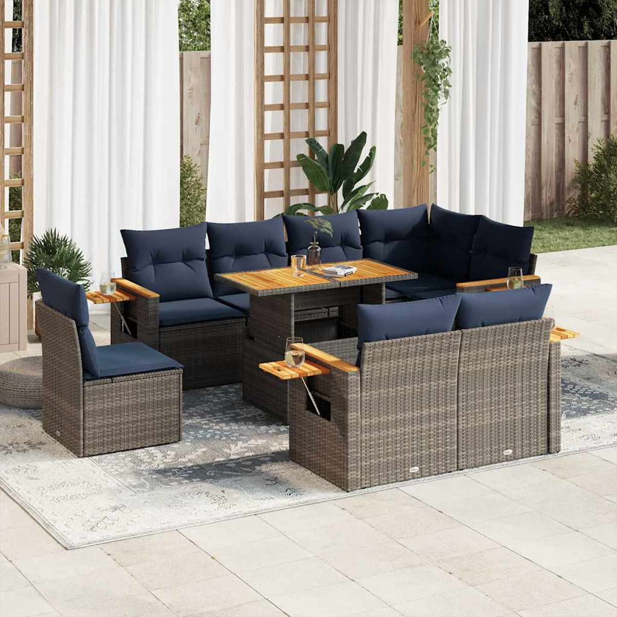 Juego de muebles de patio exterior con mimbre gris, cojines azul marino y una mesa de madera con bebidas.