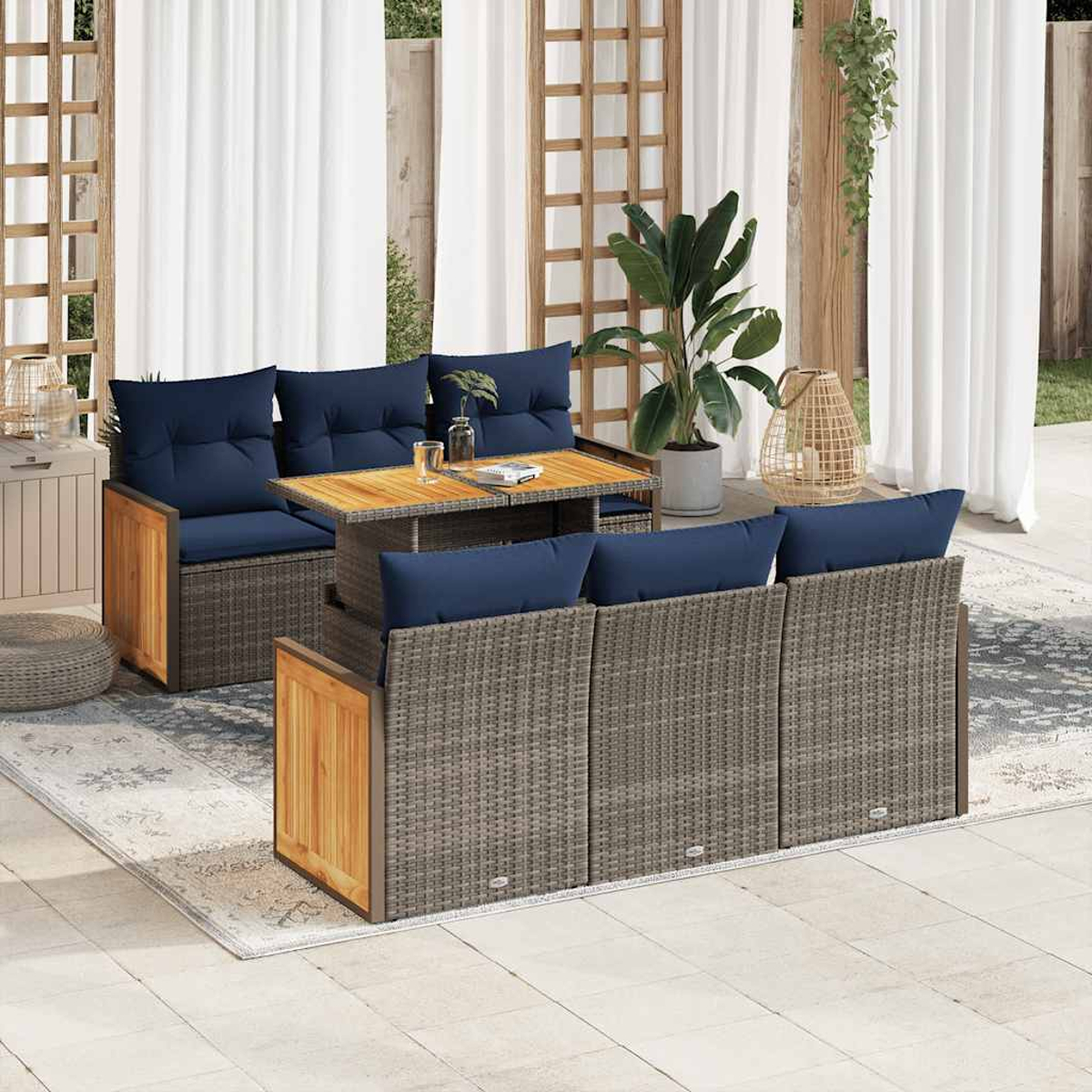 Conjunto de asientos al aire libre con muebles de ratán gris, cojines azules y mesa de madera. Cortinas y planta.