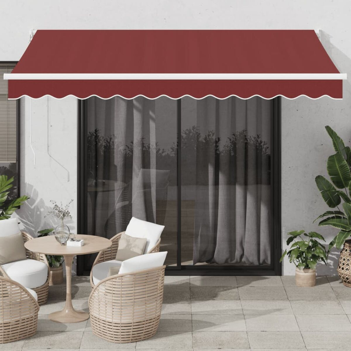 Eine Terrasse mit roter Markise, rundem Tisch und zwei weißen Stühlen. Pflanzen und Tür.