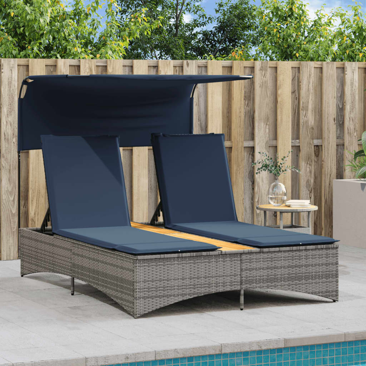Due lettini prendisole con cuscini blu sotto un tendalino, vicino a una piscina e a una staccionata di legno.