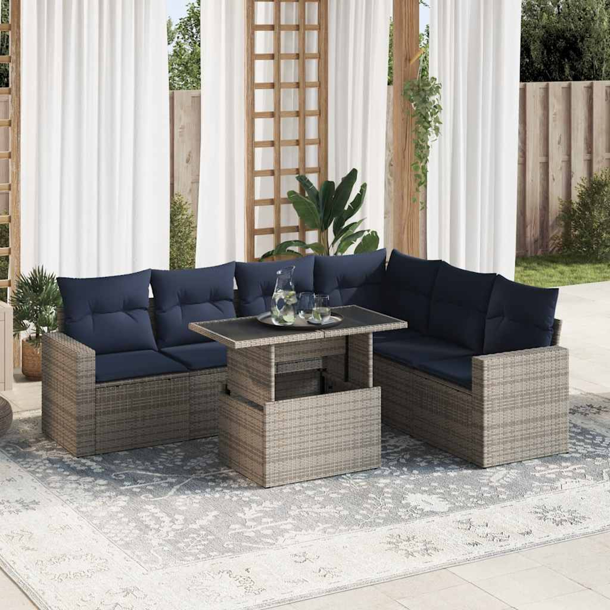 Ein graues Korbmöbel-Set mit marineblauen Kissen und einem Tisch. Der Tisch hat ein Glas darauf und einen Teppich.