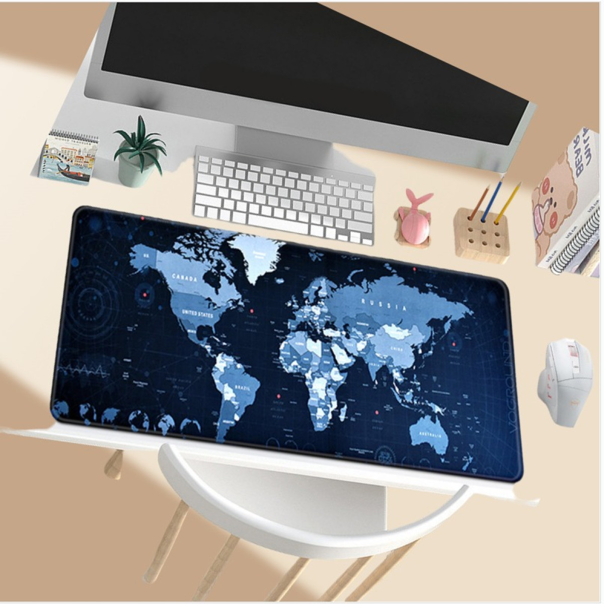 Eine Weltkarten-Schreibtischunterlage unter einem Monitor, einer Tastatur und anderen Schreibtischartikeln.