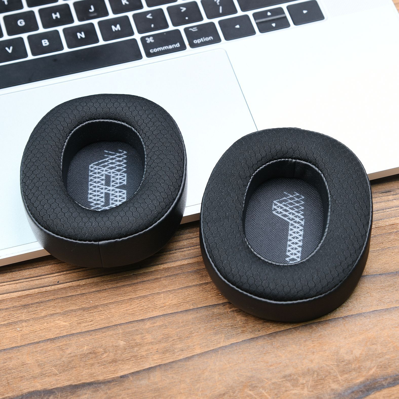 Due cuscinetti auricolari neri per cuffie su un laptop. I cuscinetti hanno un design a rete.