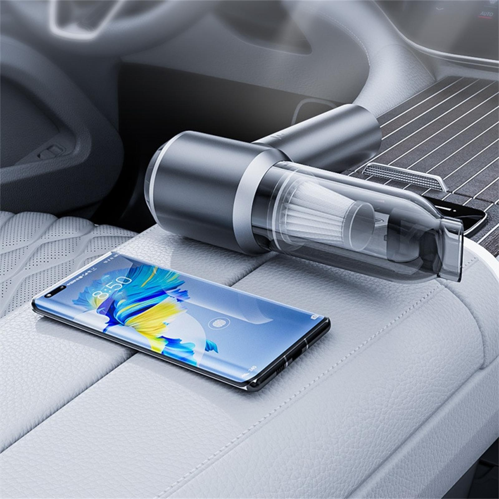 Ein silberner und schwarzer Handstaubsauger und ein Smartphone auf einem Autositz.