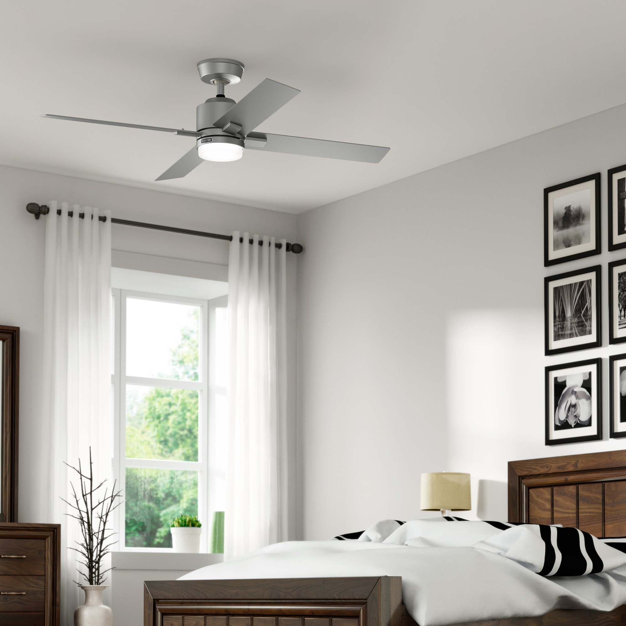 Ein Schlafzimmer mit Deckenventilator und Bett. Es gibt Fenster, Vorhänge und Kunstwerke im Raum.