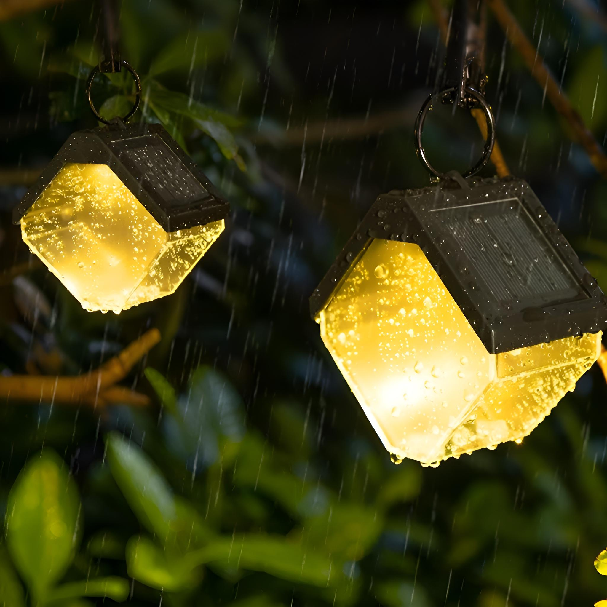 Zwei Solarleuchten im Freien hängen im Regen, mit gelbem Lichtschein.