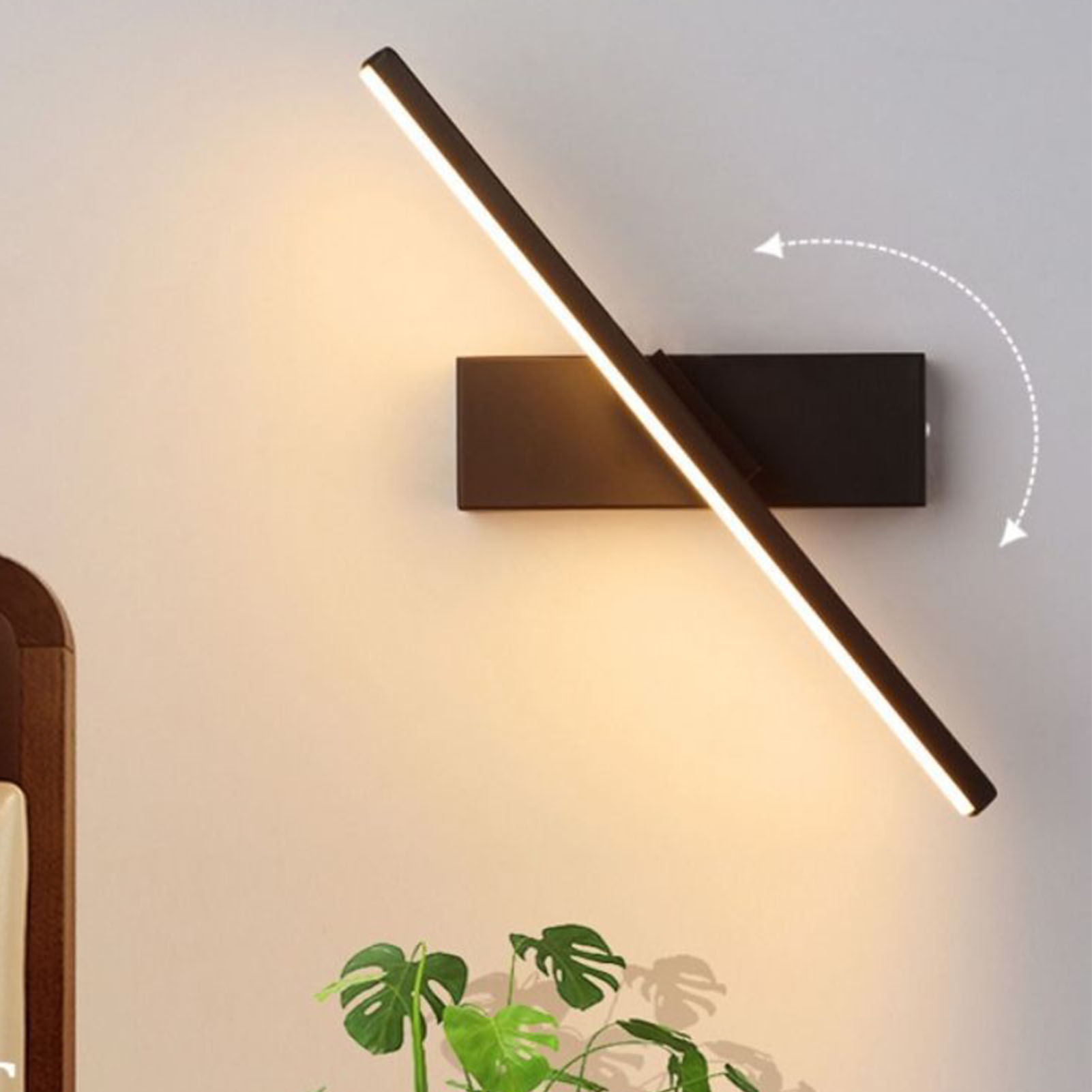 Schwarze, an der Wand montierte LED-Leuchte mit verstellbarem Arm und Pflanze.