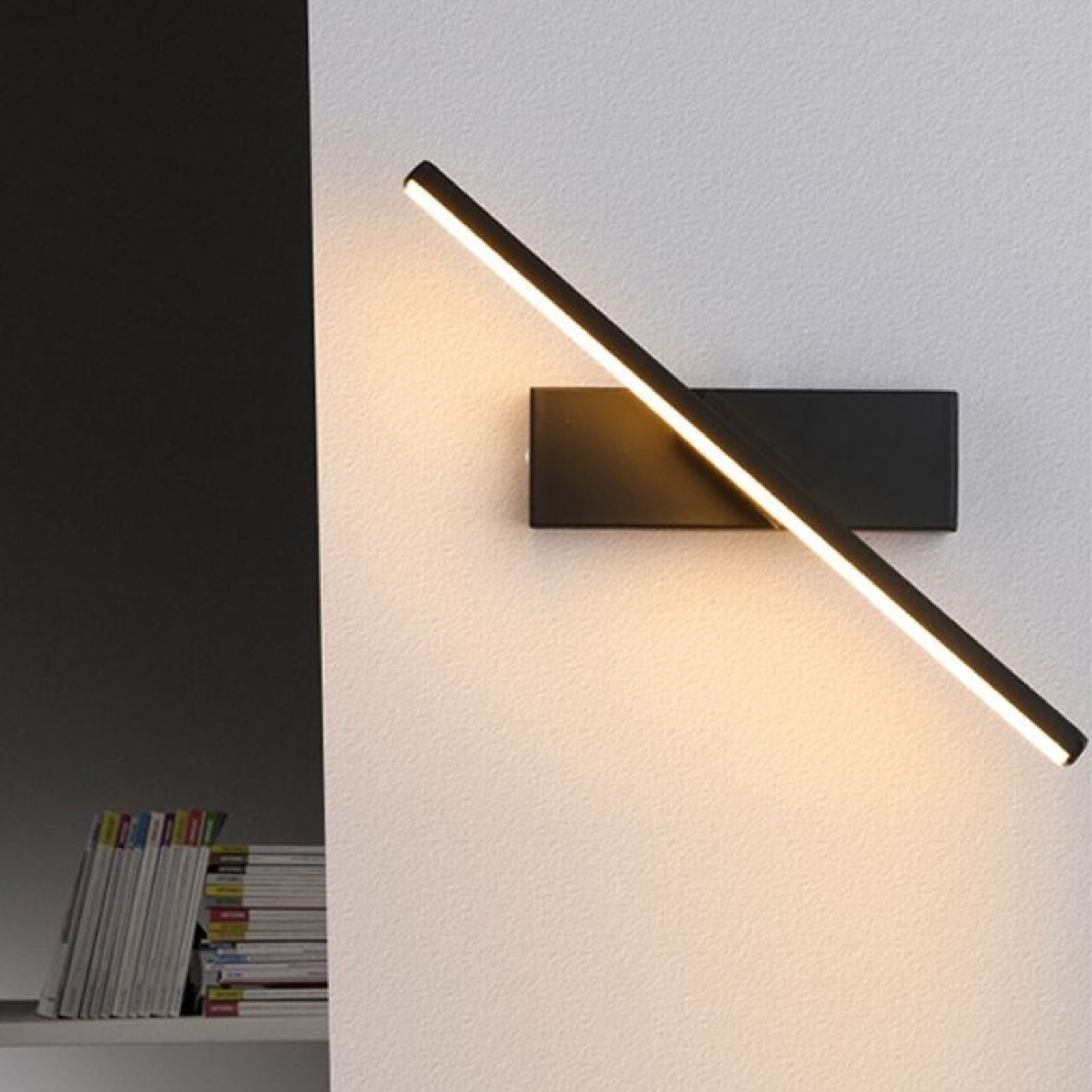 Eine schwarze Wandleuchte mit einem langen, dünnen Lichtbalken, der sich diagonal erstreckt.