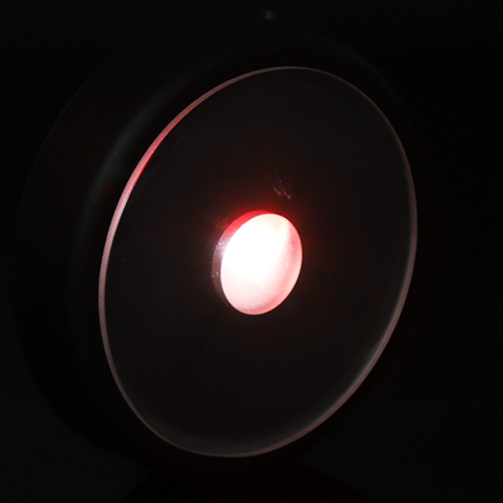 Nahaufnahme eines kreisförmigen, schwarzen Lichts. Ein rotes Licht scheint aus der Mitte.