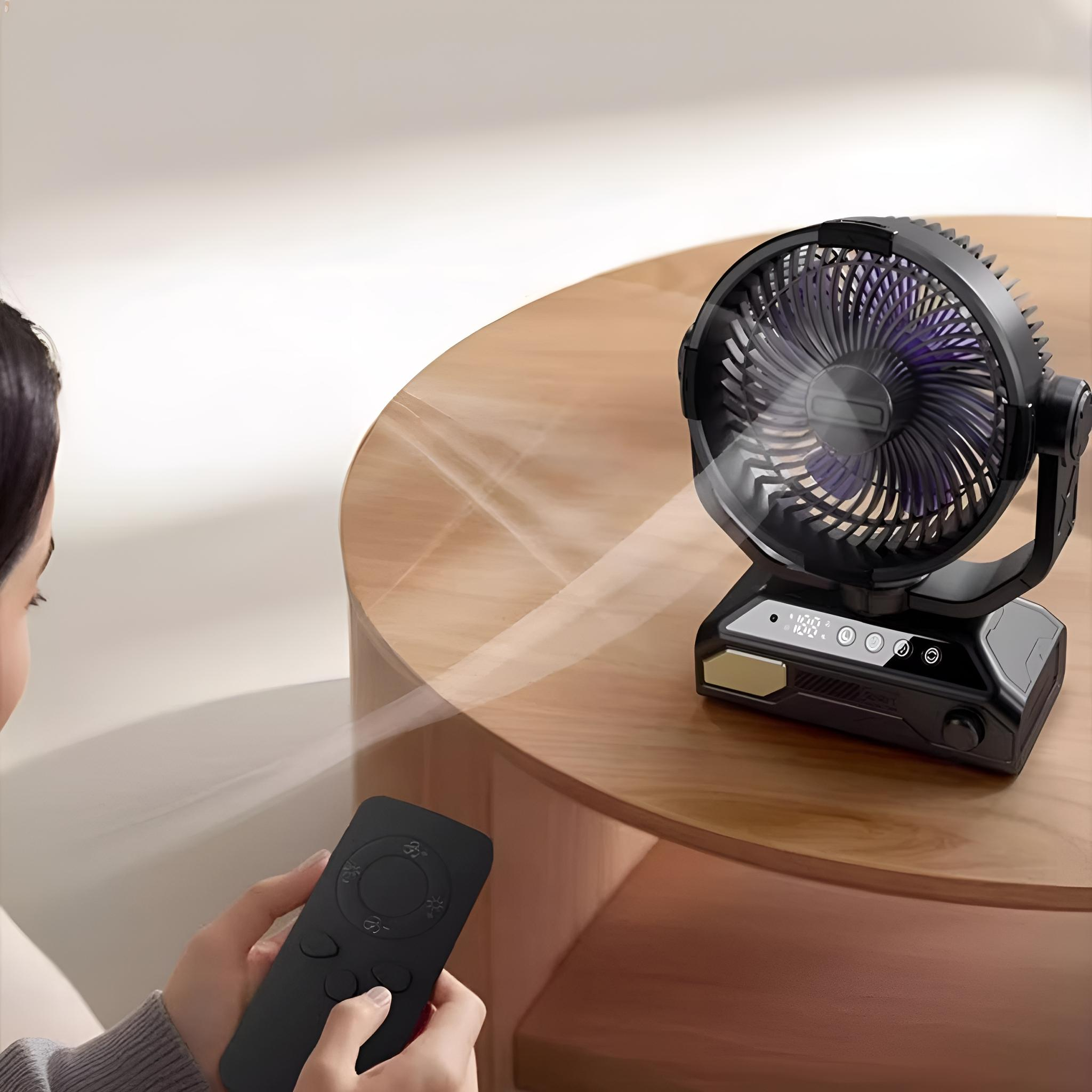 Ein schwarzer Ventilator auf einem Tisch mit einer Fernbedienung im Vordergrund. Der Ventilator ist angewinkelt, eine Frau hält eine Fernbedienung.