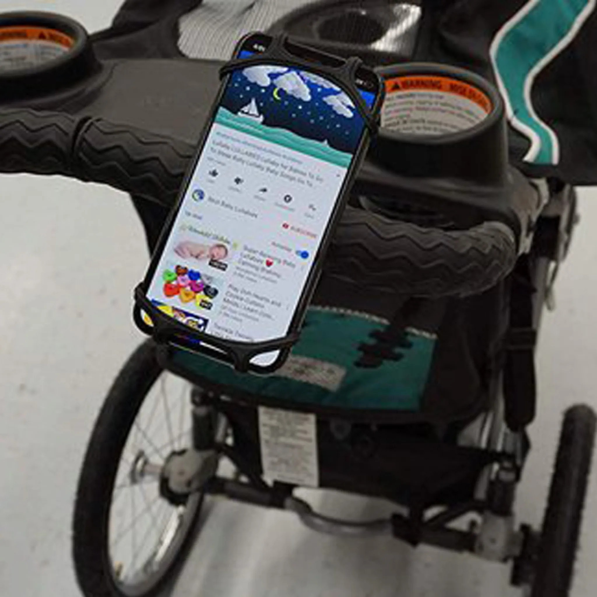 Ein Telefon, das an einem Kinderwagen befestigt ist, zeigt ein Video eines Babys mit Sternenhimmel im Hintergrund.