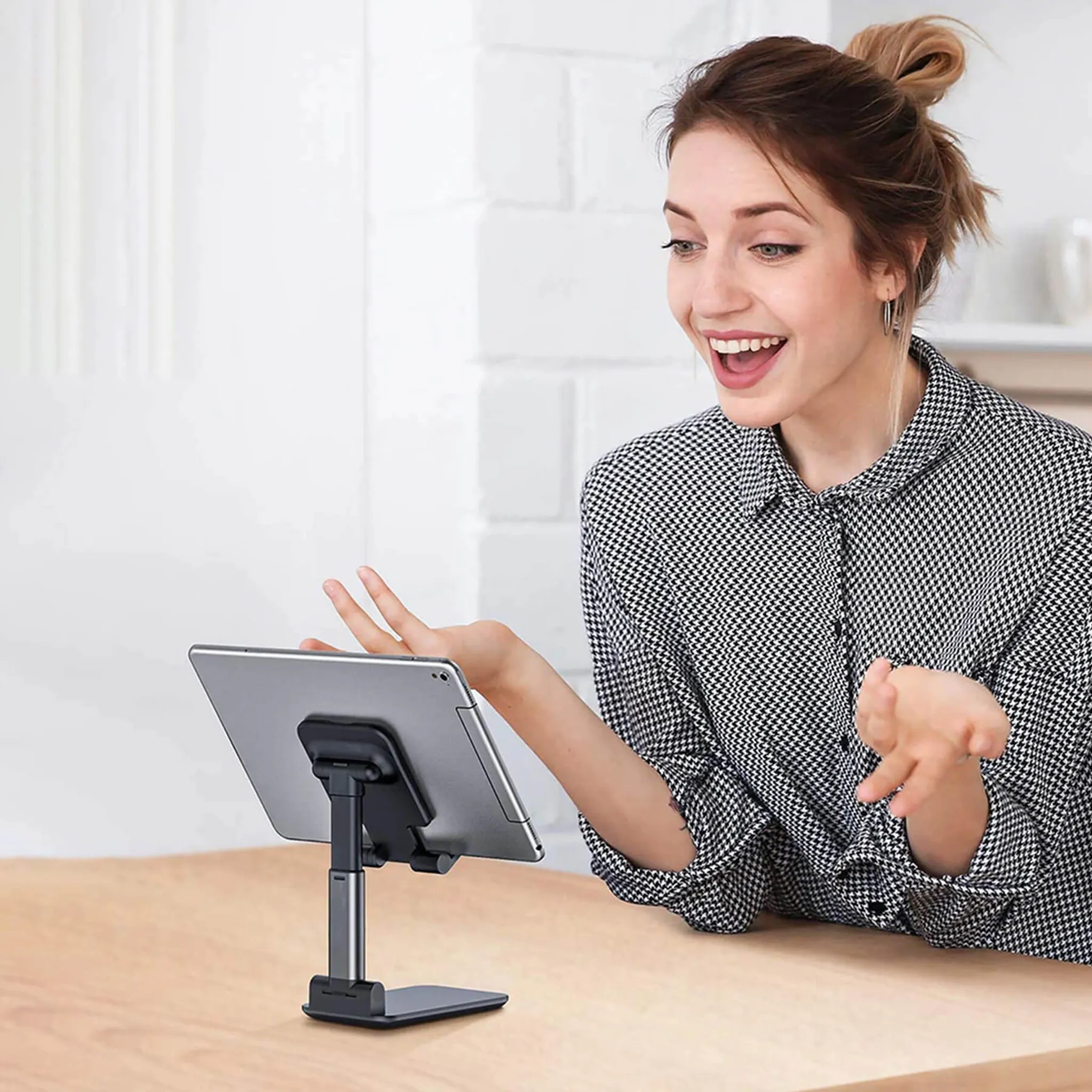 Eine Frau lächelt und schaut auf ein Tablet auf einem Ständer. Der Ständer ist schwarz.