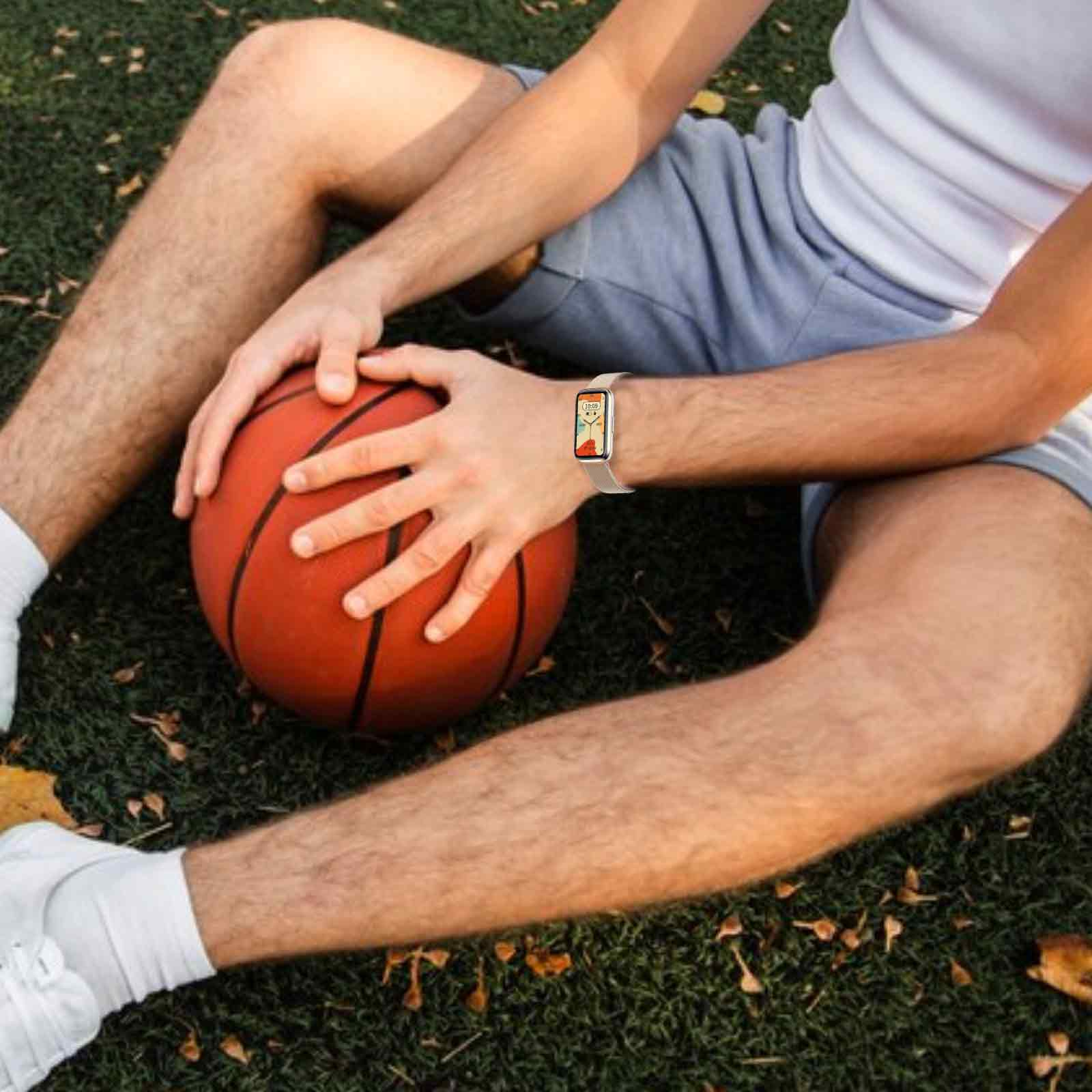 Eine Person sitzt mit einem Basketball und trägt eine Smartwatch.