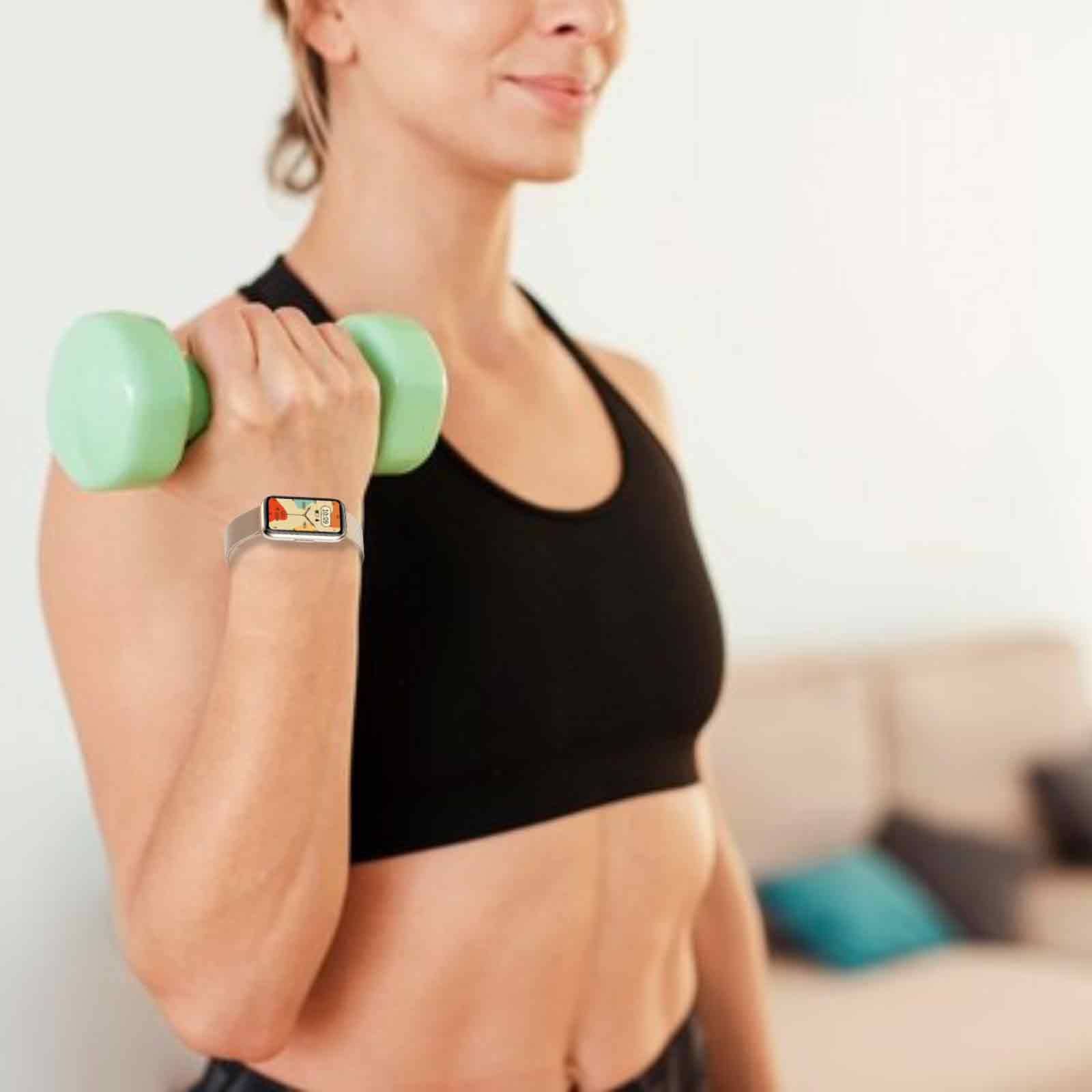 Frau hält eine Hantel, trägt einen Sport-BH und eine Smartwatch. Die Uhr zeigt Zeit und eine Grafik.